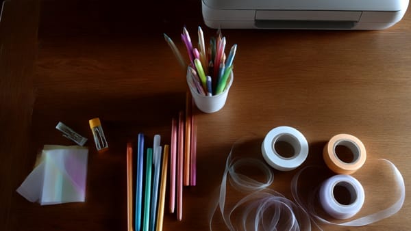 A table with pens and tape and a printer. Art supplies for the school year